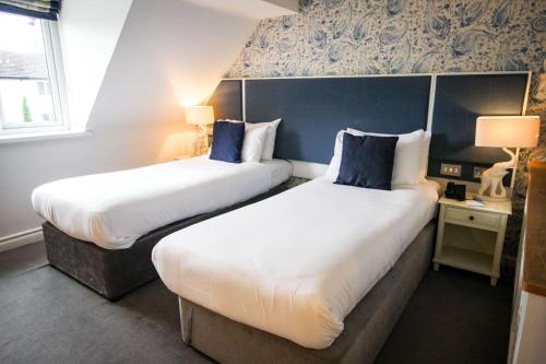two beds in a hotel room with blue walls at Thornton Hall Hotel & Spa in Heswall