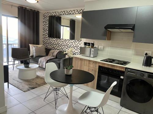 a kitchen and living room with a table and chairs at The Lagoon Exquisite Apartments in Pretoria