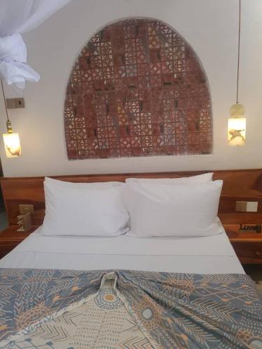 a bed with white pillows and a brick wall at Sand and Sunset in Kendwa