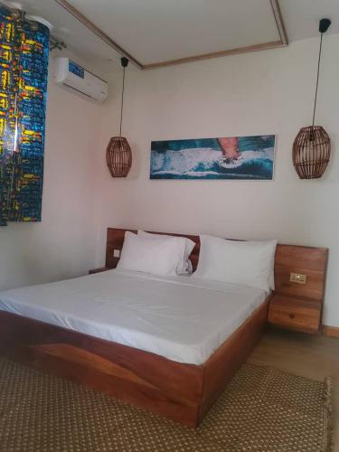 a bedroom with a bed with white sheets and a window at Sand and Sunset in Kendwa