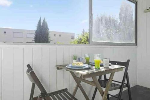 une table avec une assiette de nourriture et deux chaises dans l'établissement T2 avec loggia à 10 min du centre de Montpellier, à Montpellier