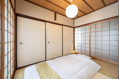 a small room with a bed with white doors at くりくまのいえNostalgic JPN House cottage 2BDR in Marugame