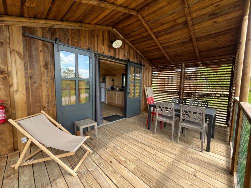 eine Holzterrasse mit einem Tisch und Stühlen darauf in der Unterkunft Ushuaïa Villages La Buissonnière Lodges in Chisseaux