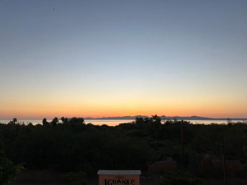 a sunset over the ocean with a sign in the foreground at Tres Iguanas Apart Hotel - New, cozy & spacious flats, short walk to beach in Loreto