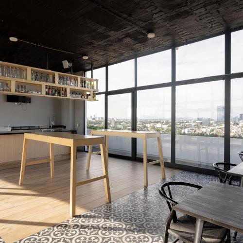 a room with tables and chairs and large windows at Departamento 2 habitaciones en la Americana in Guadalajara