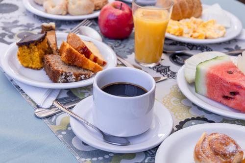 a table with plates of breakfast foods and a cup of coffee at Pousada Piri Paim in Pirenópolis