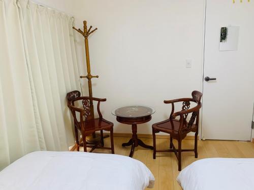 a room with two beds and a table and chairs at guest house REST in Kubogayato