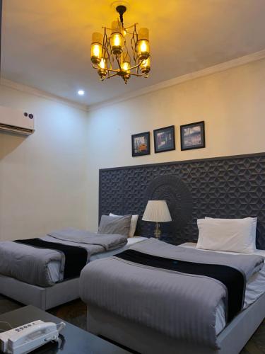two beds in a hotel room with a chandelier at Hotel Swan Suites in Lahore