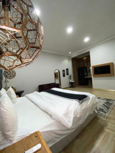 a bedroom with a large white bed and a chandelier at Hotel Swan Suites in Lahore