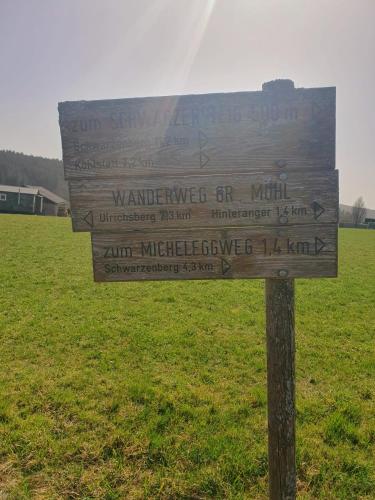 a wooden sign in the middle of a field at Böhmerwald fun in Schwarzenberg am Bohmerwald