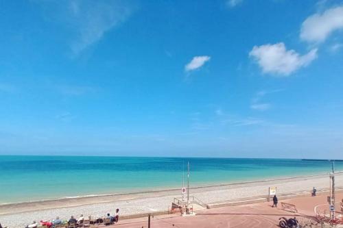 a beach with a group of people standing on the sand at Vue imprenable sur la mer BY HOLIDIEPPE in Dieppe