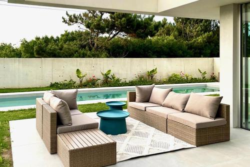a patio with wicker furniture next to a swimming pool at Villa Mar & Luz, Porto, Mindelo Beach in Mindelo