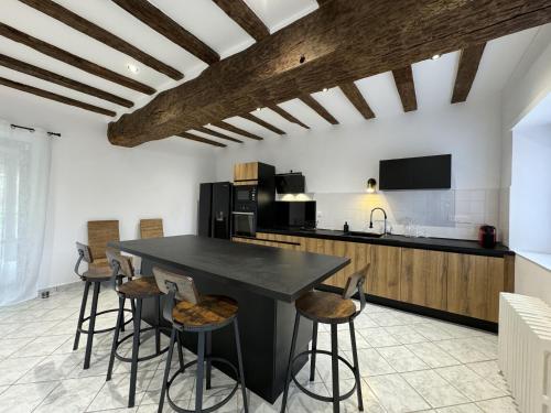une cuisine avec un îlot noir et des tabourets de bar dans l'établissement Le Saltimbanque - 6 pers - Campagne - Rêve au Mans, à Mansigné