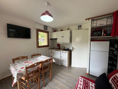 une cuisine et une salle à manger avec une table et un réfrigérateur dans l'établissement Appartement cosy avec terrasse, proche télécabine - FR-1-198-88, à Châtel