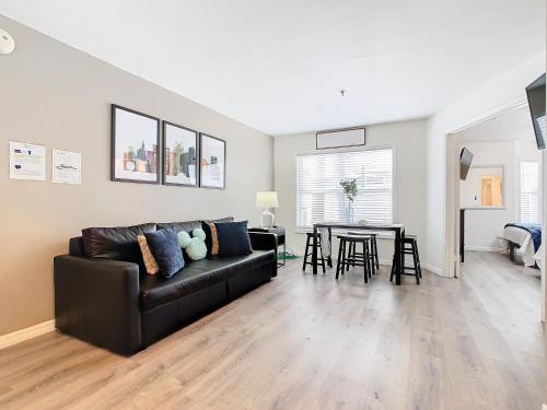a living room with a black leather couch and a table at Be Our Guest! 1 Bedroom Condo Near Disney Parks! in Orlando