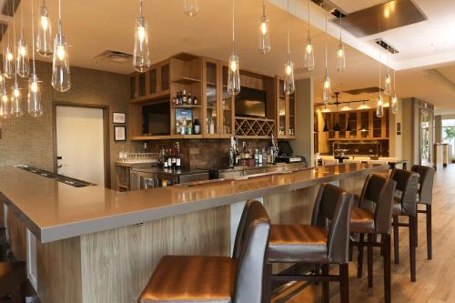a bar in a restaurant with brown chairs and lights at Hilton Garden Inn Arvada/Denver, CO in Arvada