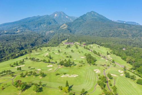 an aerial view of a golf course with mountains in the background at 関温泉 吉野屋温泉旅館 in Myoko
