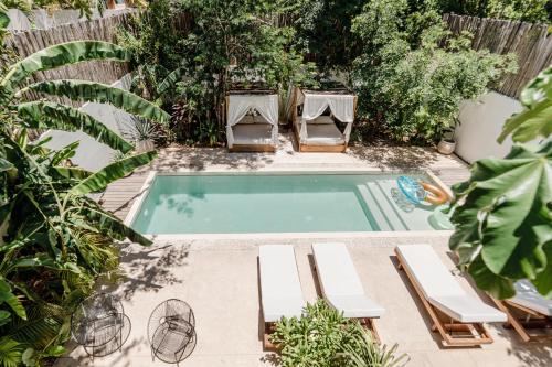 a swimming pool with two lounge chairs and a table at Villa Sorella in Aldea Zama 24Hrs Security, 5min to the beach in Tulum