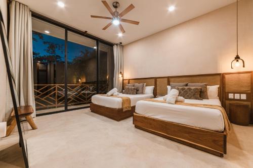 a bedroom with two beds and a large window at Villa Sorella in Aldea Zama 24Hrs Security, 5min to the beach in Tulum