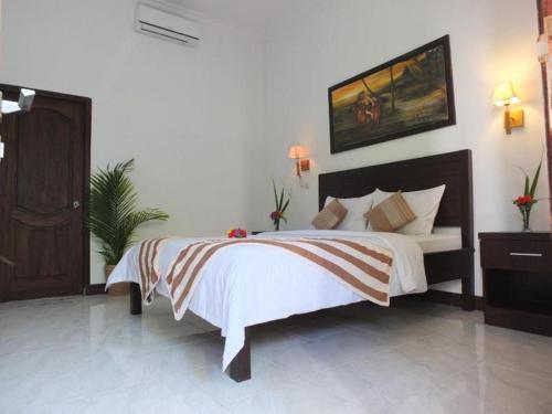 a bedroom with a bed and a painting on the wall at Ricel Homestay in Gili Trawangan