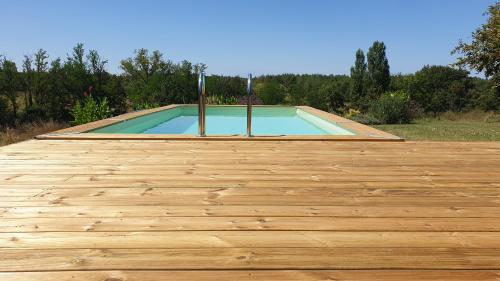 une petite piscine avec une terrasse en bois dans l'établissement Les Gites Sur La Colline - 21 m2 studio with shared pool, à Montignac-de-Lauzun