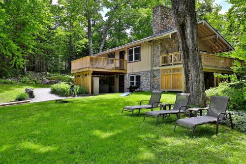 a house with four chairs sitting in the yard at Fun In Fun Out Ski Home - Upper Unit, Renovated 3BR-2BA, Hot Tub, Close to Resort in Killington