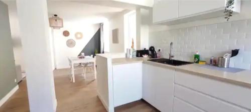 une cuisine blanche avec un évier et une table dans l'établissement L'idylle dieppoise, à Dieppe