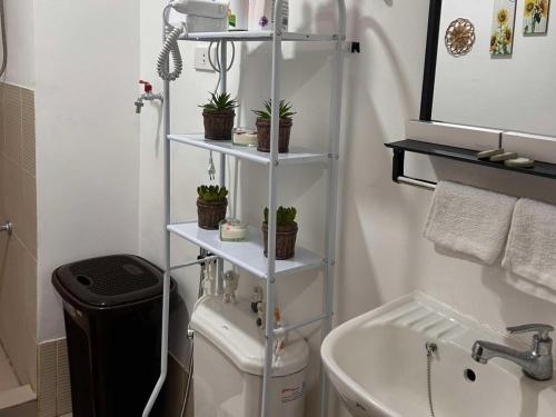 a bathroom with a white shelf with potted plants on it at SyHOME-Suites in Trece Martires