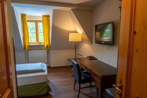 a room with a desk and a bed and a television at Hotel Restaurant Taverna in Eching