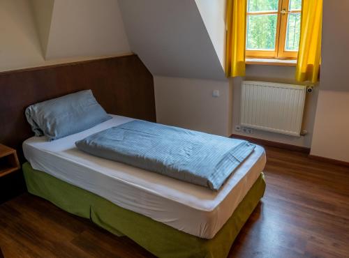 a bedroom with a bed with blue sheets and a window at Hotel Restaurant Taverna in Eching