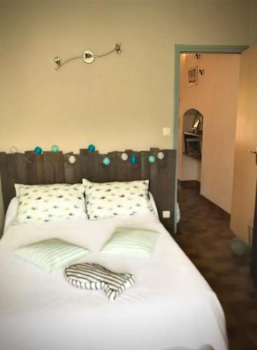 un lit avec des draps blancs et des oreillers dans une chambre dans l'établissement Charmant séjour au cœur des vignes de Banyuls, à Banyuls-sur-Mer