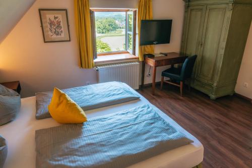 a bedroom with a bed and a desk and a window at Hotel Restaurant Taverna in Eching