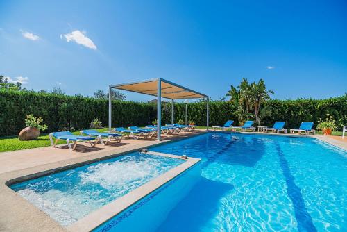une piscine avec des chaises bleues et un auvent dans l'établissement Villa La Rosaleda - By Dream Villas Pollensa, à El Port