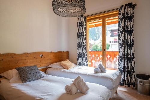 deux lits dans une chambre avec une fenêtre dans l'établissement Chalet Mouflon des Neiges, aux Gets