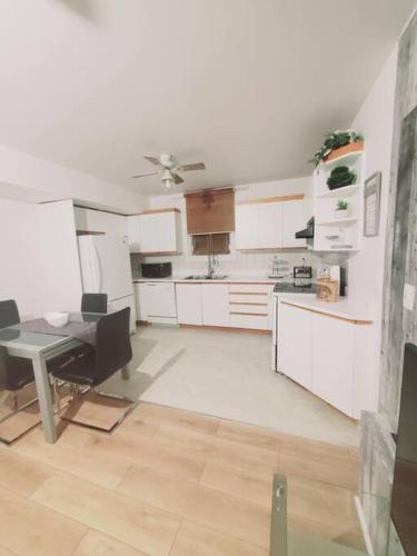 a kitchen with white cabinets and a table in it at Le cosy for familys, home work in Longueuil