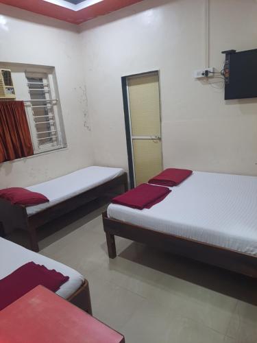 a room with two beds and a window at Ram niwas hotel in Mumbai