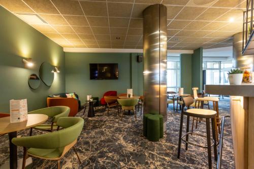 a restaurant with green walls and tables and chairs at Novotel Bourges in Bourges