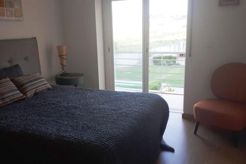a bedroom with a bed and a chair and a window at Sweet Ericeira Surf, Apartment in Ericeira