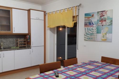 a kitchen with a table and chairs and a refrigerator at Sweet Ericeira Surf, Apartment in Ericeira