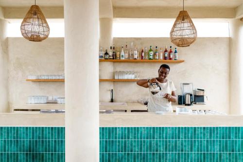 een man aan een bar met een glas wijn bij GARDEN EDEN Lodge in Jambiani
