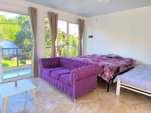a living room with a purple couch and a bed at Departamentos Boiko in Leandro N. Alem