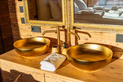 two gold bowls on a wooden vanity with a mirror at Das Kitz - Chalet Steuerberg XL Kitzbühel in Kitzbühel