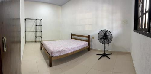 een slaapkamer met een bed en een ventilator op de vloer bij Cantinho da serra in Ubatuba