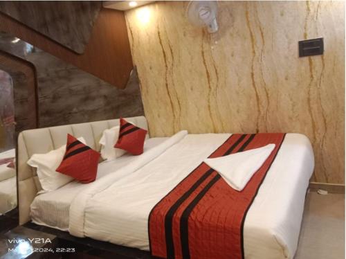 a bedroom with a bed with red and black pillows at Hotel Ganpati in Patna