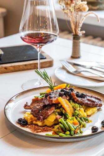 a plate of food on a table with a glass of wine at Seehotel Lichtenberg in Lichtenberg
