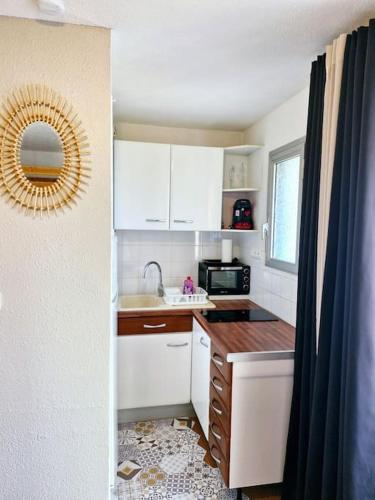 La cuisine est équipée de placards blancs, d'un lavabo et d'un miroir. dans l'établissement Studio cabine pour 4 équipé proche port Cap d'Agde, au Cap d'Agde