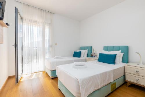 two beds in a room with a window at Apart hotel M S KATUNJANIN in Herceg-Novi