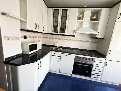 a kitchen with white cabinets and a microwave at Borja el Marino in Balmaseda