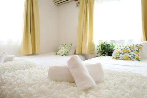 a white bed with two white towels on it at 西川口ハウス最大12名家族団体 in Toda