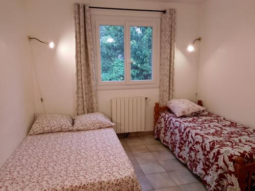 two beds in a room with a window at Chambre 2 personnes a Calvisson Gard in Calvisson